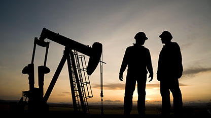 workers in silhouette at drill site