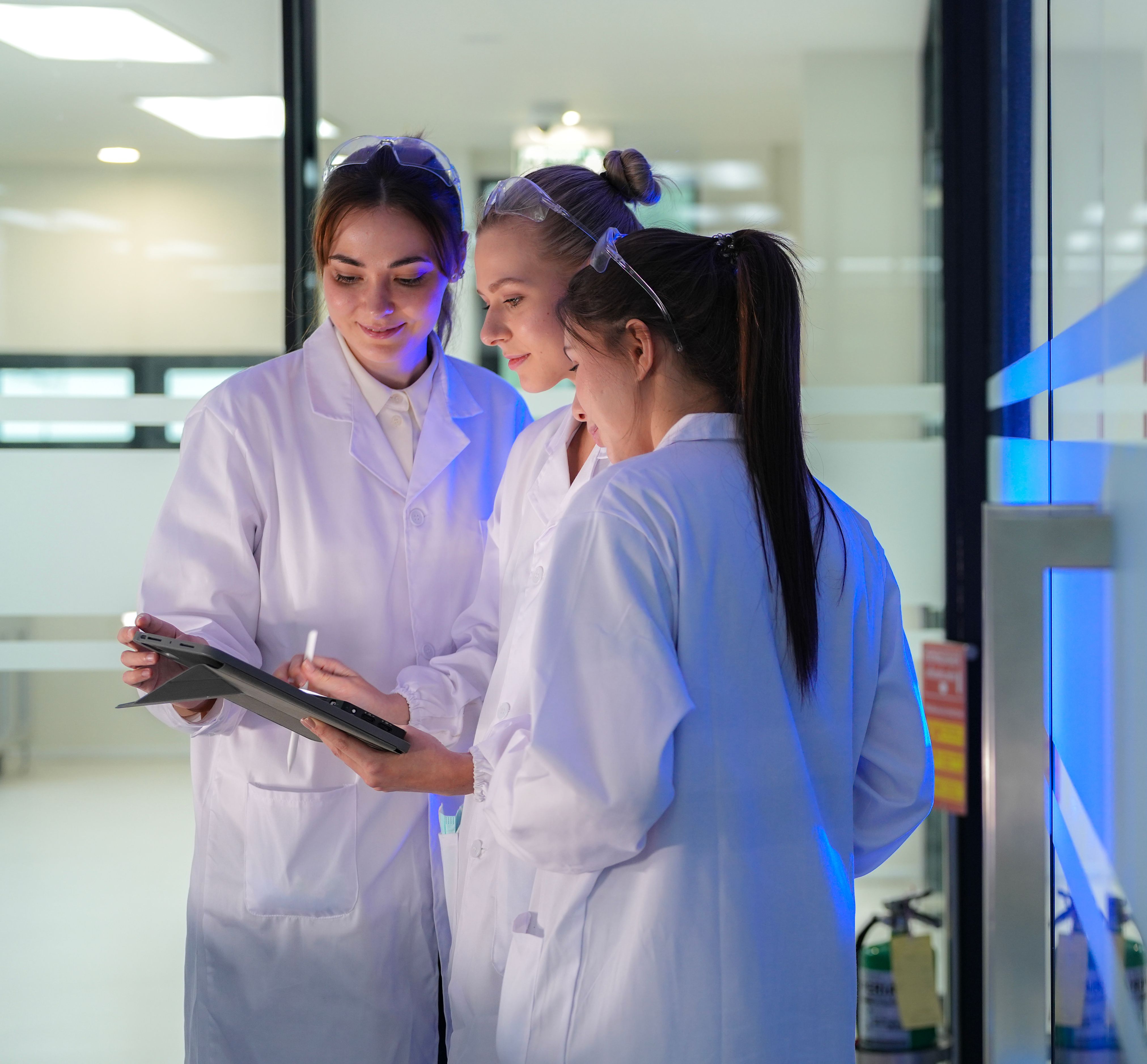 Close in on scientists comparing data on a tablet in a pharmaceutical testing laboratory setting