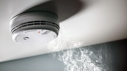 Smoke detector and interlinked fire alarm in action background