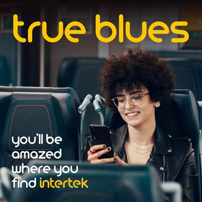 A woman smiling while looking at her phone on a bus